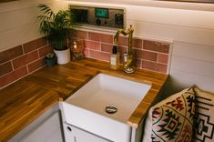 a kitchen sink with a wooden counter top next to a potted plant on a shelf