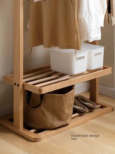 a wooden shelf with two baskets and clothes hanging on it