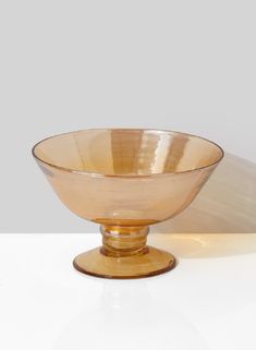 a gold colored bowl sitting on top of a white table next to a black cat