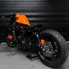 an orange and black motorcycle parked in front of a garage door on a metal platform