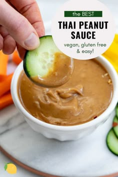 the best thai peanut sauce in a white bowl with cucumbers and carrots