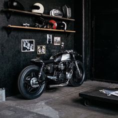 a black motorcycle parked in a garage next to a wall with pictures on the walls