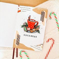 an open christmas card with candy canes next to it and a notebook that says december