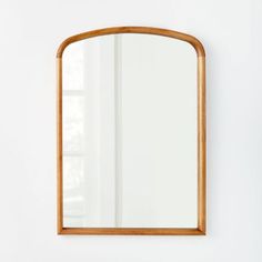 a wooden mirror hanging on the wall next to a white wall with a plant in it