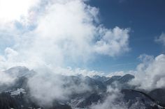 the sun shines brightly on snow covered mountains in the distance, while clouds hover over them