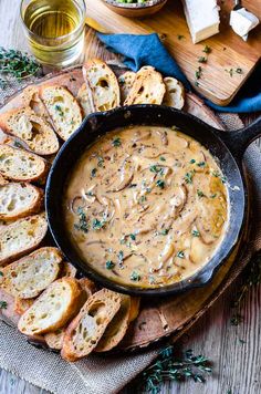 a skillet filled with bread and gravy on top of a wooden cutting board