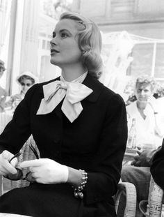 black and white photograph of woman sitting at table with other people in the back ground