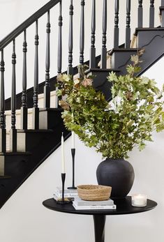 a vase with some flowers on top of a table next to a stair case and railing