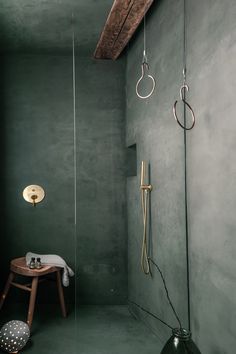 a bathroom with green walls and flooring, including a stand alone shower head in the corner