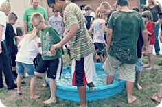 a group of people standing around a blue pool filled with water and playing in it