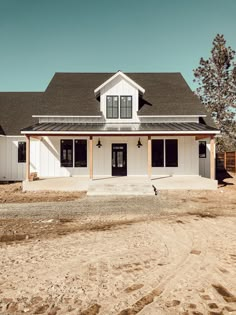 a large white house sitting on top of a dirt field