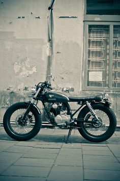 a black motorcycle parked on the side of a street next to a building with windows