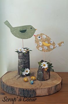 two birds are sitting on top of some stumps with daisies in their beaks