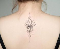 the back of a woman's neck with a lotus tattoo on her left shoulder