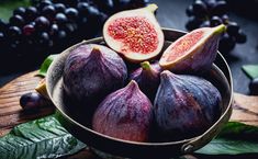 figs and grapes in a bowl on a wooden table