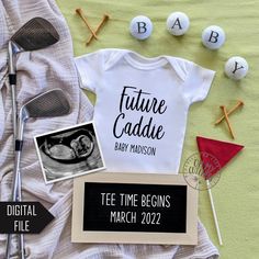 a baby announcement with golf tees and other items on the bed next to it