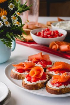 there are several pieces of bread that have salmon on them and flowers in the background