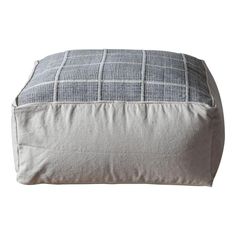 a gray and white checkered blanket sitting on top of a floor cushion next to a pillow