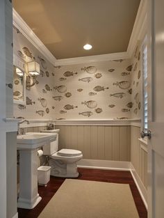 a bathroom with a toilet, sink and bathtub next to a wallpapered wall