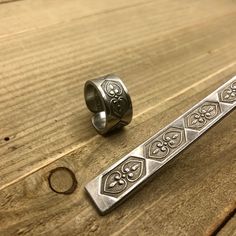 two silver rings sitting on top of a wooden table next to an object that looks like it is made out of metal