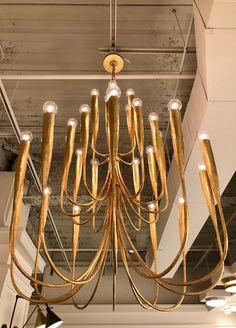 a gold chandelier hanging from the ceiling in a room with exposed ceilings and lights