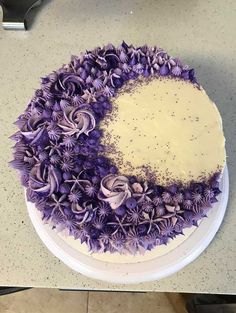 a cake decorated with purple flowers and sprinkles sits on a counter top