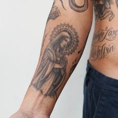 a man's arm with tattoos on it and an image of the virgin mary