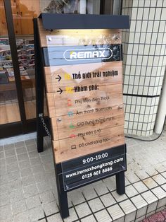 a wooden sign sitting on the side of a sidewalk next to a store front door