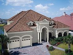 an aerial view of a house with two garages and palm trees in the foreground