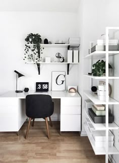 a white desk and shelves in a room with wood flooring, bookshelves and plants