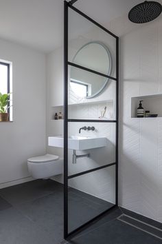 a bathroom with a toilet, sink and mirror on the wall next to a window