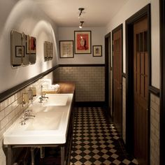 a bathroom with two sinks and pictures on the wall next to it's doors