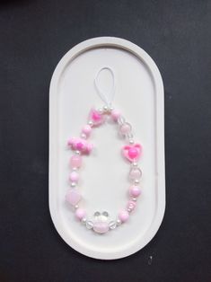 a pink and white beaded bracelet on a tray