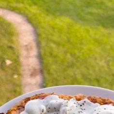 a white plate topped with food on top of a wooden table next to a grass covered field