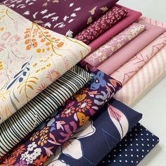 a stack of different colored fabrics sitting on top of each other in front of a white table