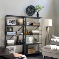 a living room filled with furniture and bookshelves next to a wall mounted clock