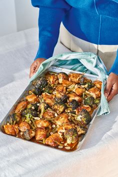 a woman is holding a bag full of chicken and broccoli