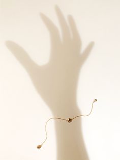 a hand casting a shadow on a wall with a beaded bracelet attached to it