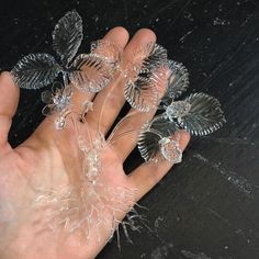 a person's hand holding three glass flowers