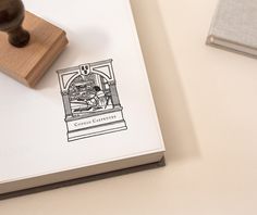 a rubber stamp sitting on top of a white book next to a wooden stamper