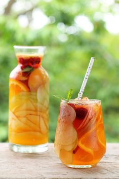 two glasses filled with drinks sitting on top of a wooden table next to each other