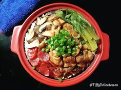 a red bowl filled with meat and veggies on top of a black table