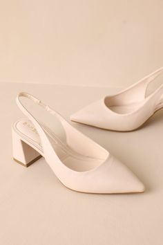 a pair of white high heeled shoes sitting on top of a table