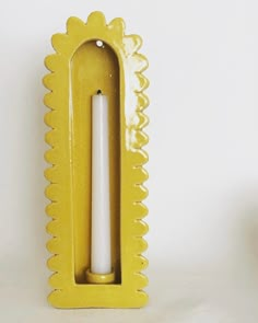 a yellow candle holder with a white candle in it