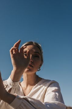 a woman holding her hand up to the sky