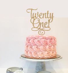 there is a cake with pink frosting on it and the words twenty one written in gold