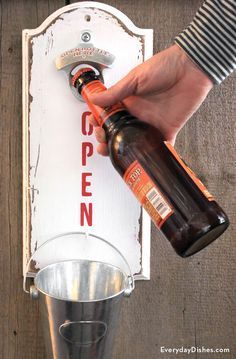 a person is holding a beer bottle in front of a sign that says open on it