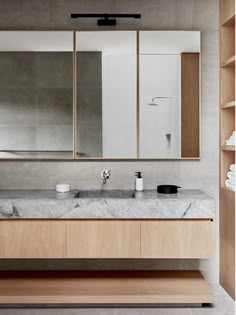 a bathroom with marble counter tops and wooden cabinets, along with white towels on the shelves