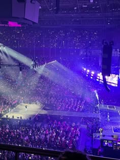 an arena filled with lots of people and bright lights shining down on the audience at a concert