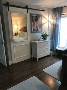 a living room with white furniture and blue curtains on the window sill, hardwood flooring